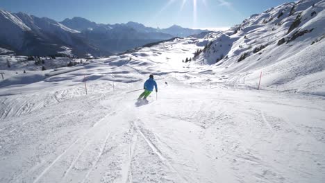 FOLLOW-TRACKING-SLOW-MOTION:-very-good-young-skier-skiing-on-a-beautiful-winter-day-on-perfect-slope-with-amazing-mountain-scenery-at-ski-resort-in-the-swiss-Alps-during-cloudless-day