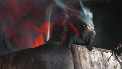 Justieren-Brennender-Holzscheite-Mit-Metallwerkzeug