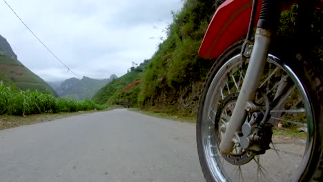 First-person-view-of-a-narrow-winding-rough-road-that-cuts-through-the-mountains-and-valleys-of-northern-Vietnam