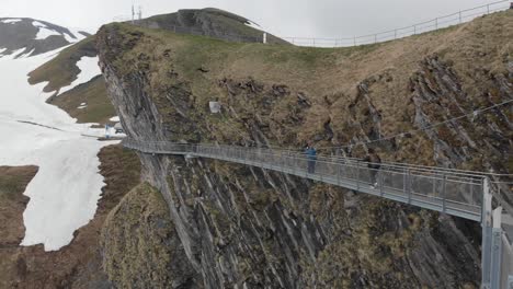Pedestrian-Suspension-Bridge-Over-Cliff-with-Two-People-Walking-in-the-Winter