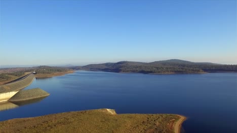 Aerial-shot,-pulling-back-from-Wivenhoe-Dam-and-panning-across-the-smooth-blue-waters-of-Lake-Wivenhoe,-in-Queensland's-picturesque-Somerset-Region