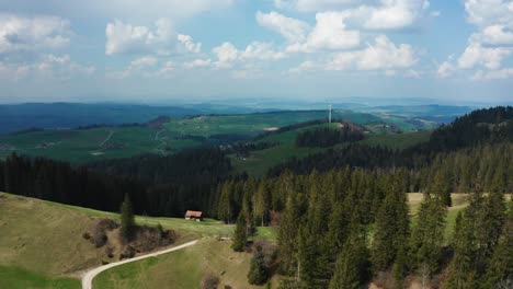 aerial-view-of-single-windmill-in-the-swiss-countryside-with-pine-trees-,-renewable-energy-from-wind-power-turbines