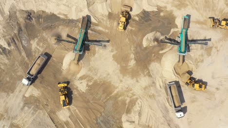 Aerial-view,-machinery-working-at-clay-quarry,-heavy-loaders,-large-trucks,-bulldozers,-excavators,-Sand-quarry,-Mining,-Truck-takes-raw-materials-from-the-quarry,-Large-clay-warehouse