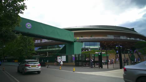 view-of-the-entrance-of-Wimbledon-with-the-Court-number-1-in-front,-cars-and-people-passing-by,-the-footbridge-is-used-to-connect-the-queue-to-the-various-courts