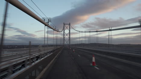 Motion-shot-from-a-vehicle-crossing-a-Forth-road-bridge-with-wonderful-sunset-light-and-clouds-in-Edinburgh,-Scotland