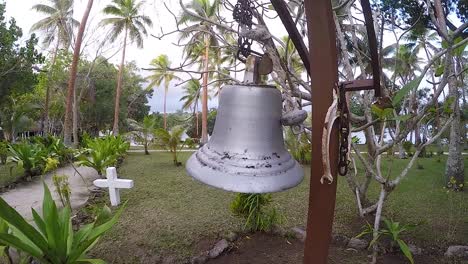 A-female-person-ringing-a-large-bell-near-an-island-cemetery