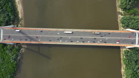 Stadtauto-Bewegt-Sich-An-Der-Autobahnbrücke-Auf-Hintergrund,-Glatter-Flussoberfläche,-Drohnenansicht