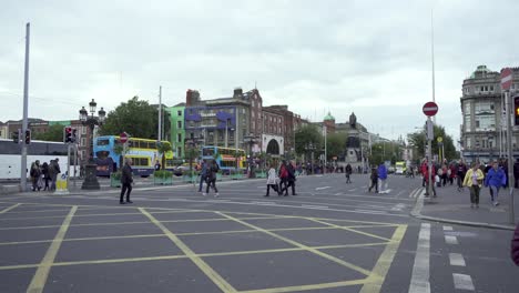 Crossing-in-Dublin-city-centre-with-pedestrians,-traffic-and-touristic-buses