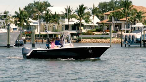 Fishing-boat-with-men---women-motoring-up-the-Manatee-Pocket-waterway-in-Stuart-Florida,-recreational-fun-on-vacation-holiday-seasons