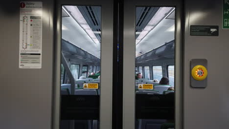 Symmetrische-Innenaufnahme-Des-GWR-Zuges,-Der-Sich-Dem-Bahnhof-Filton-Abbey-Wood-Nähert,-Mit-Sitzenden-Passagieren-Und-Türen-Im-Vordergrund