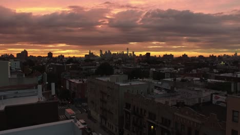 Rising-NYC-sunset-aerial-view-over-Brooklyn-rooftops-revealing-Manhattan-skyline-4K
