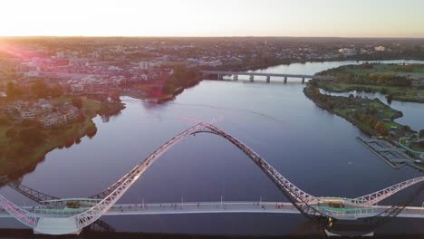 Aerial-view-of-a-Swan-River-with-backwards-camera-motion-revealing-Matagarup-Bridge-with-people-going-to-the-other-side