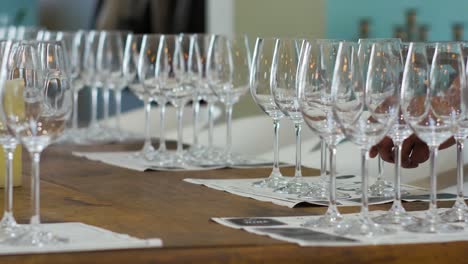 Waiter-setting-wine-glasses-on-table-for-wine-tasting,-low-perspective-static-shot