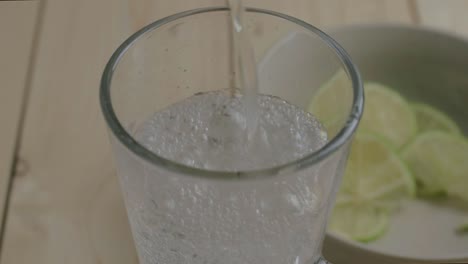 Gießen-Sie-Ein-Glas-Erfrischendes-Kohlensäurehaltiges-Wasser-Mit-Limettenscheiben-Ein
