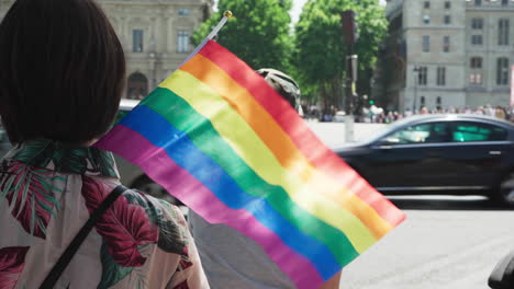Die-Gay-Pride-Flagge-Weht-Im-Wind-Inmitten-Einer-Kleinen-Menschenmenge,-Die-Auf-Den-Gay-Pride-Marsch-Wartet