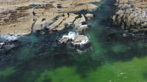 Waves-crashing-on-the-rocky-coast-slide-down-drone-footage