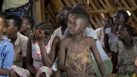 Un-Grupo-De-Niños-Sentados-En-Un-Banco-Mirando-Alrededor-En-Un-Centro-Comunitario-En-África