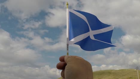Eine-Schottische-Flagge,-Die-In-Der-Hand-Gehalten-Wird,-Weht-Am-Himmel