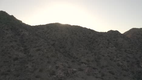 drone-flying-down-mountain-with-sun-setting-behind-it