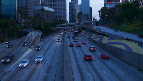 Zeitraffer-Des-Autobahnverkehrs-Und-Der-Innenstadt-Von-Los-Angeles-In-Der-Abenddämmerung-Mit-Lichtspuren