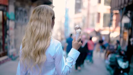 Young-beautiful-girl-eats-ice-cream-while-walking-at-narrow-street-in-Europe