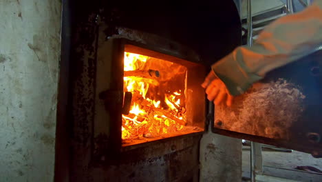 slow-motion-man-throwing-wood-into-a-furnace-3