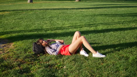 Beautiful-young-hispanic-college-student-resting-and-taking-a-nap-on-a-grassy-field-between-classes-on-campus