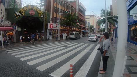 Traffic-driving-across-zebra-pedestrian-crossing-in-front-of-outdoor-market