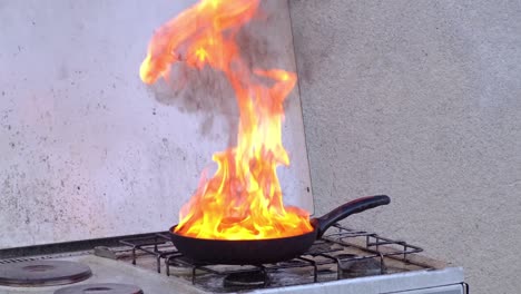 Kitchen-fire-demonstration,-igniting-hot-fat-in-pan-with-blow-torch
