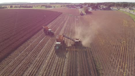 Aerial-rotating-view-from-the-front-of-a-harvester-picking-corn-for-next-years-harvest-while-another-tractor-turns-around-in-the-background