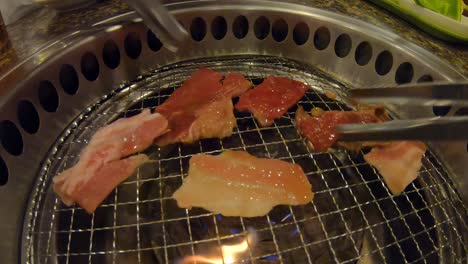 Tongs-flipping-grilled-meat-on-yakiniku-Japanese-BBQ