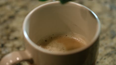 Close-up-of-sweetener-dripping-in-the-coffee-inside-a-mug