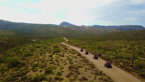 Aerial-drone-shot-of-four-UTV's-driving-through-the-Arizona-desert-on-a-cloudy-day