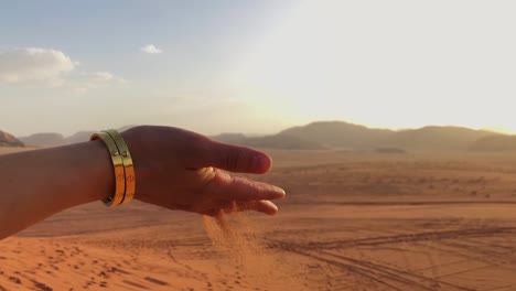 Slow-Motion-shot-of-sand-falling-through-a-woman's-hand-in-the-Wadi-Rum-Desert,-Jordan