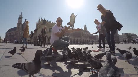 Family-of-tourists-feeding-and-interacting-with-pigeons-at-Krakow-square