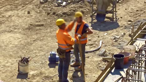 Two-blue-collar-workers-talking-on-construction-site