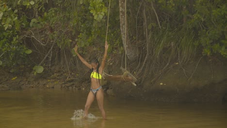 A-girl-comes-off-from-swinging-at-the-river-and-walks-towards-the-camera