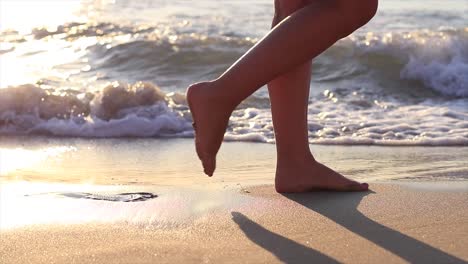 Girl-walking-on-a-sandy-beach-with-the-waves-coming-onto-it-in-slow-motion