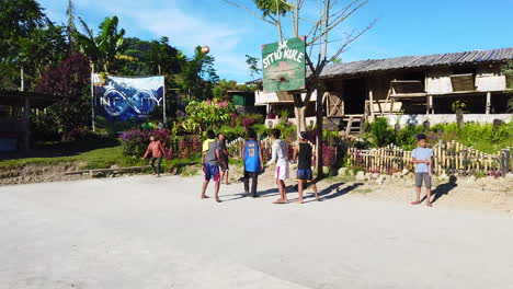 group-of-young-men-doing-basketball-in-an-open-field-with-nipa-house-and-blue-sky-in-the-background