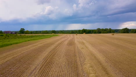 Flying-over-a-freshly-cut-hay-field-with-storm-clouds-in-the-distance
