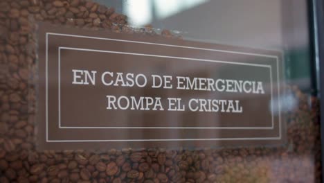 Emergency-coffee-sign-in-Spanish-"In-case-of-emergency,-break-the-glass",-footage-moving-backwards