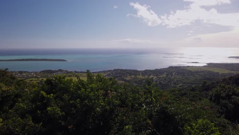 Ein-Schwenk,-Der-Sich-Rechts-Von-Der-Insel-Mauritius-Bewegt-Und-Die-Landschaft-Mit-Viel-Vegetation,-Dem-Meer,-Einer-Kleinen-Insel-Und-Einem-Klaren-Und-Atemberaubenden-Himmel-Zeigt