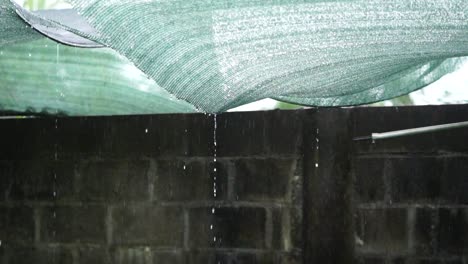 Rain-dripping-through-a-mesh-roof-cover,-slow-motion
