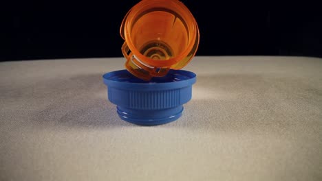 moving-past-empty-blue-bottle-cap,-slowly-pushing-into-the-entire-length-of-a-orange-prescription-pill-bottle