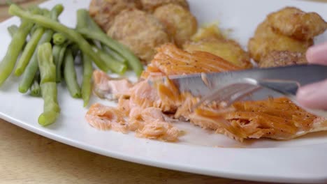 Slow-Motion-Slider-Shot-of-Eating-a-Pan-Fried-Salmon-Fillet-on-a-White-Plate-With-Vegetables