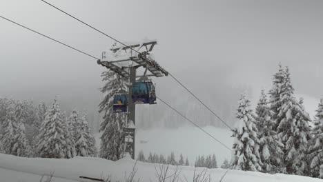 Gondola-lifts-moving-upwards-and-downwards-besides-a-pylon-during-heavy-snowfall
