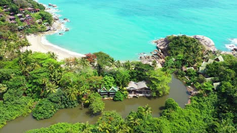 Luxurious-villas-over-rocky-coastline-of-tropical-island-with-secret-exotic-beach-and-palm-trees-forest,-Thailand