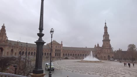 Plaza-de-Espana-in-Seville-on-a-rainy-day,-pan-left-to-tourists-with-umbrellas