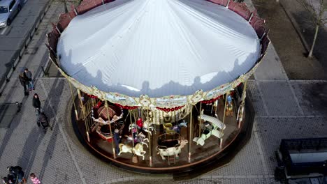Carousel-des-Allées-de-Tourny-with-children-and-parents-enjoying-a-fun-ride,-Aerial-rising-tilt-down