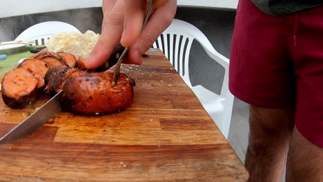 Slow-motion-video-of-a-white-man-cutting-a-sausage-on-a-wooden-board